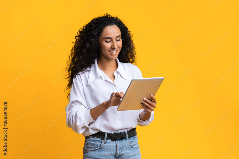 Young Woman Using Digital Tablet, Browsing Social Networks Over Yellow Studio Background Young Woman Using Digital Tablet, Browsing Social Networks Over Yellow Studio Background