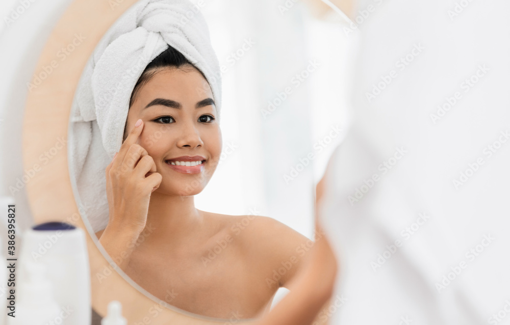 Cheerful asian woman applying eye cream at home Cheerful asian woman applying eye cream at home