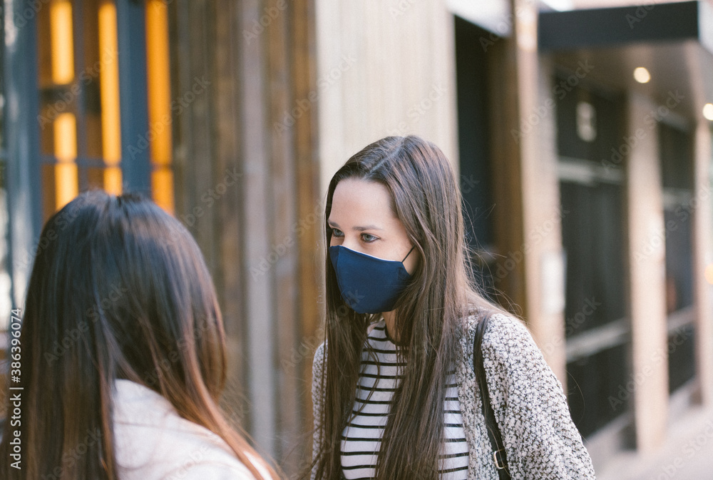 Cheerful female friends in masks in city Cheerful female friends in masks in city