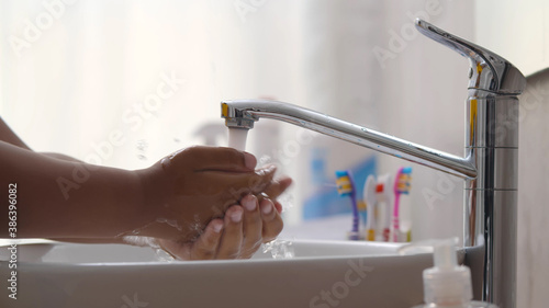Close up of african child using liquid soap and washing hands in bathroom