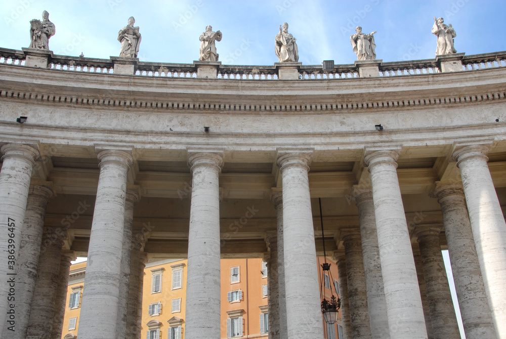 The famous colonnade of St. Peter's Square with statues in the Vatican state that is formed by large columns of travertine in a circular shape.