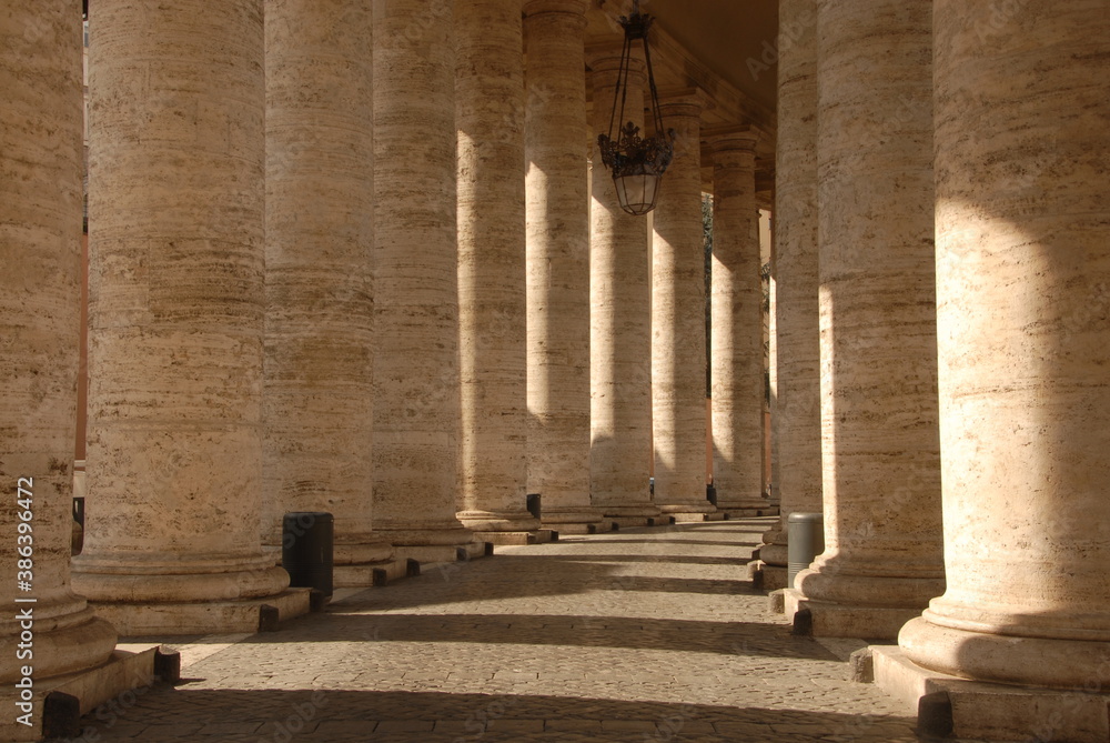 The famous colonnade of St. Peter's Square with statues in the Vatican state that is formed by large columns of travertine in a circular shape.