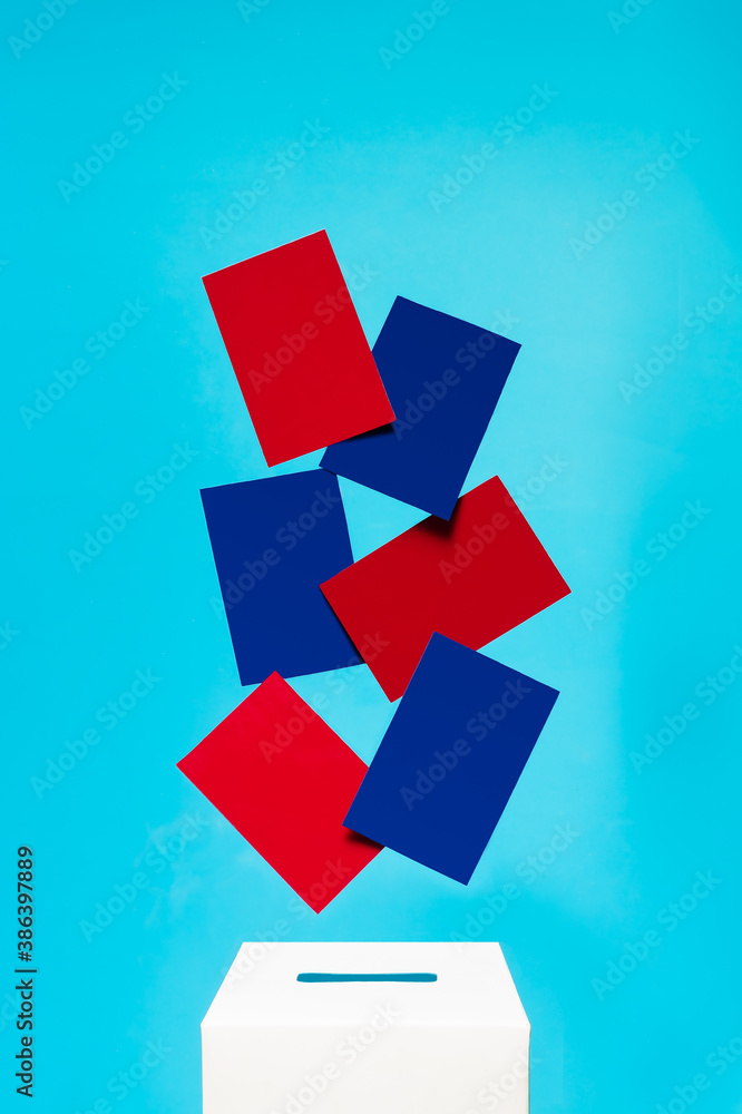 election concept - blue and red cards fall into a white voting box with a slot, the background is blue, levitation election concept - blue and red cards fall into a white voting box with a slot, the background is blue, levitation