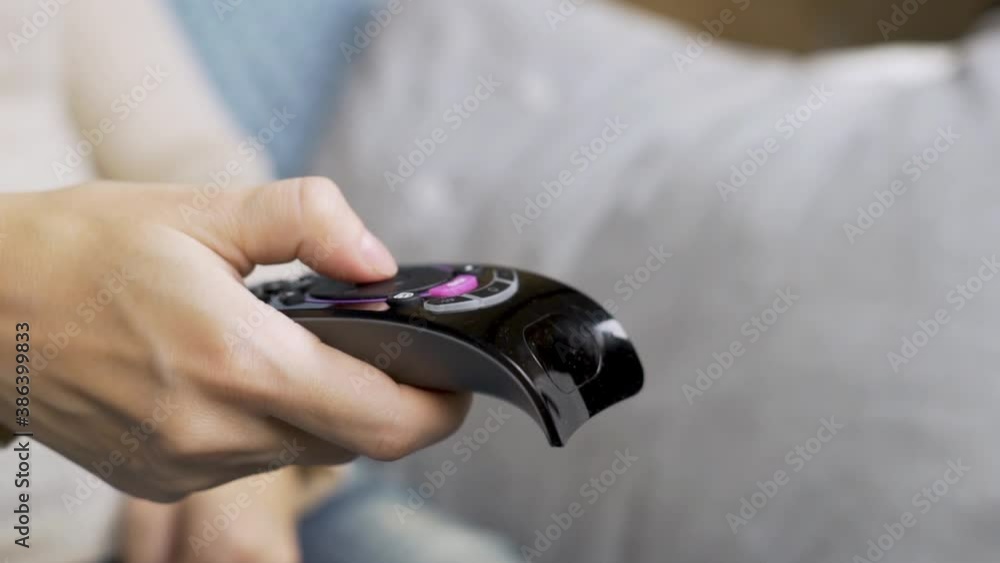 The Human Hand Turns on the Remote, the Hand Presses the Buttons on the TV Remote. Close-up of the Hand and TV Remote The Human Hand Turns on the Remote, the Hand Presses the Buttons on the TV Remote. Close-up of the Hand and TV Remote