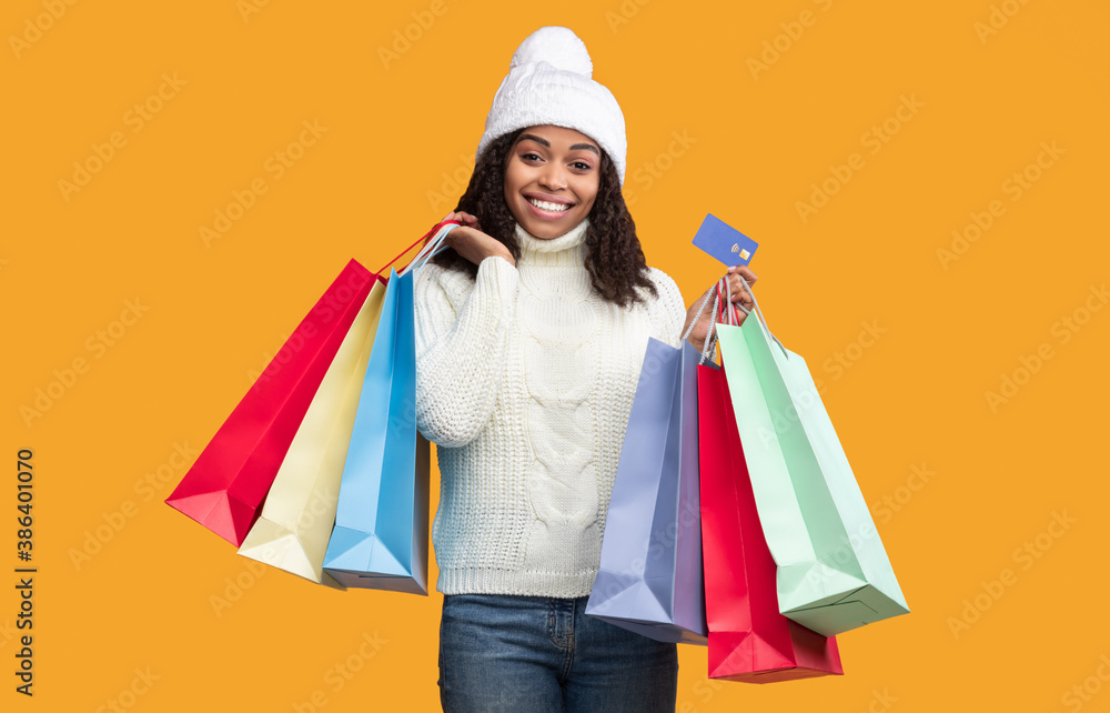 Smiling black woman holding credit card and shopping bags