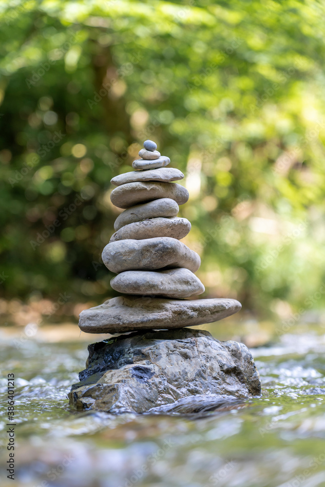 Obraz premium Relaxed view of a pyramid of stones balanced on a river water