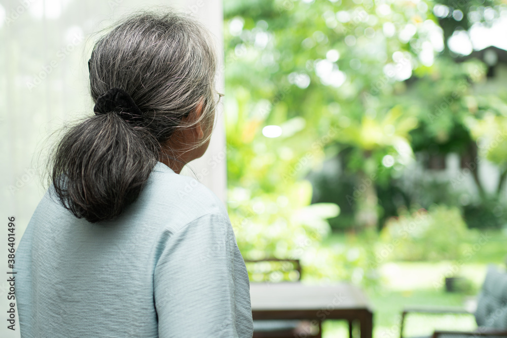 A sad old elderly woman uses Walker for standing in front of windows and looking outside and feeling lonely. Concept of depression caused by illness and Elderly caregivers A sad old elderly woman uses Walker for standing in front of windows and looking outside and feeling lonely. Concept of depression caused by illness and Elderly caregivers