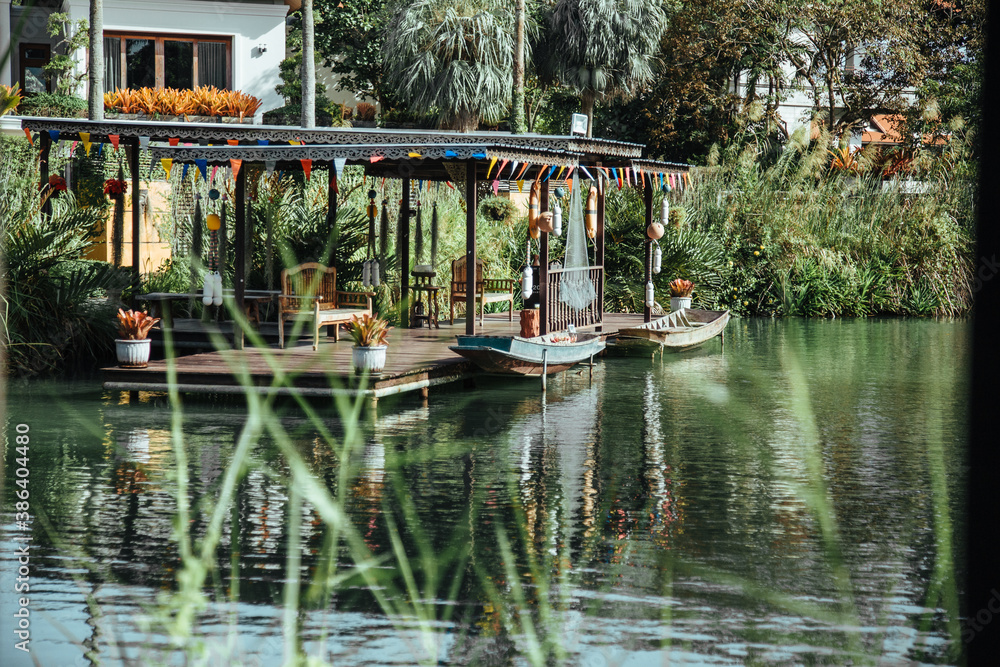 Obraz premium Thailand - 2019. Phuket Botanic Garden. Part of the recreation area by the water with boats, reeds and other greenery.