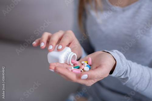 Committing suicide concept. Hopeless young woman pouring handful of pills from jar, closeup