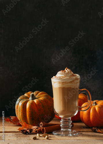 Spice pumpkin latte with cream foam, cinnamon stick, leaf and orange pumpkins