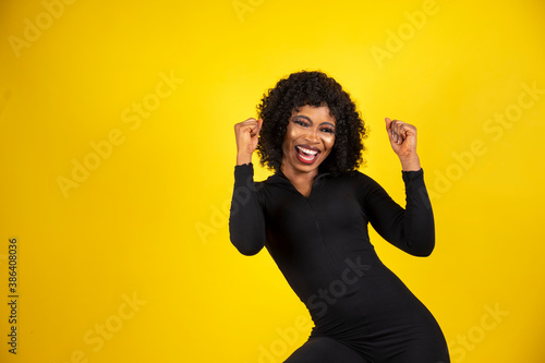 a young beautiful african lady isolated over yellow background feeling excited