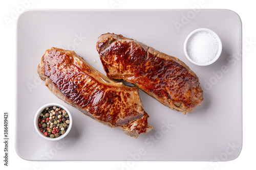 Striploin steak. Two prepeared beef steaks on gray plate isolated on white. Top view. photo