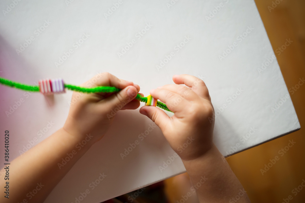 child stringing beads on string. development of baby's fine motor
