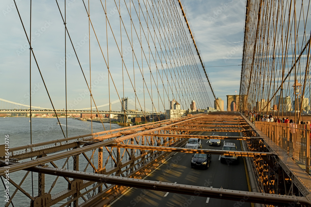Fototapeta premium View from the Brooklyn Bridge to the central part of the city with skyscrapers against the backdrop of the setting sun. New York, USA.