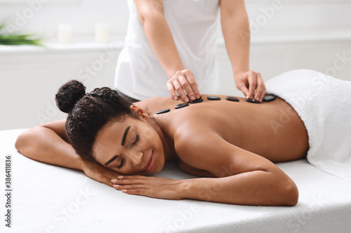 African american woman having hot stone massage at spa