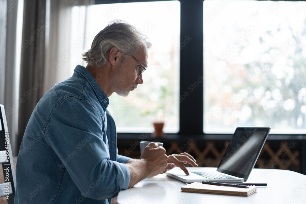 Middle-aged man working from home-office on laptop Middle-aged man working from home-office on laptop