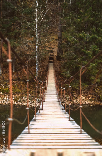 Beautiful rope hanging wooden bridge over the river. autumn landscape