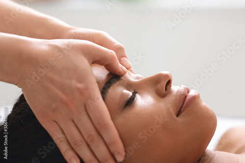 Massage therapist rubbing african american lady forehead