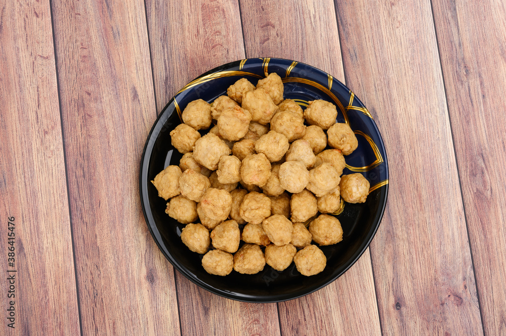 Meat or Fried Shrimp Balls placed in a black plate and put on the wooden table Meat or Fried Shrimp Balls placed in a black plate and put on the wooden table