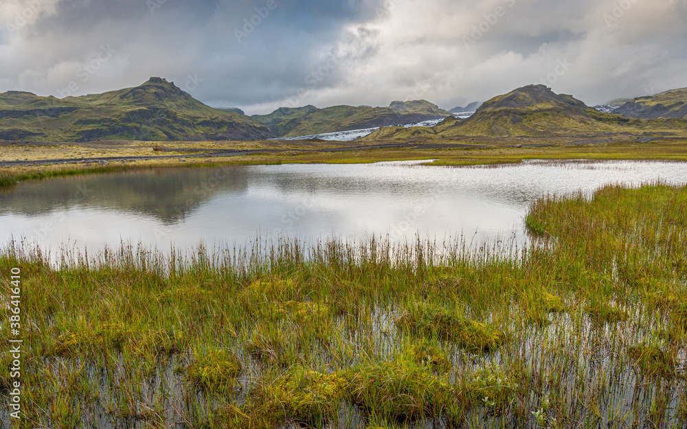 Landscape in the south of Iceland with mountains, a glacier and a lake under an overcast sky