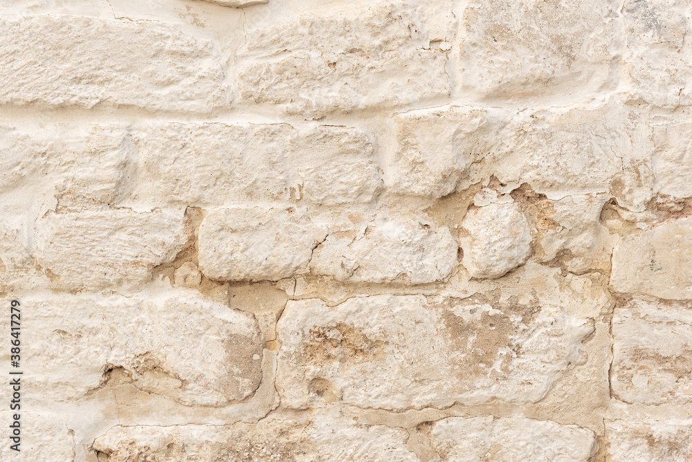 Old fashioned surface of historical building wall made of weathered brown bricks covered with white flaked stucco at bright sunlight extreme close view Old fashioned surface of historical building wall made of weathered brown bricks covered with white flaked stucco at bright sunlight extreme close view
