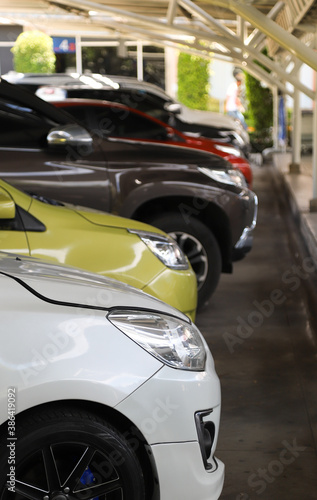 Closeup of front side of white car with other cars parking in indoor parking area. Vertical view. © Amphon