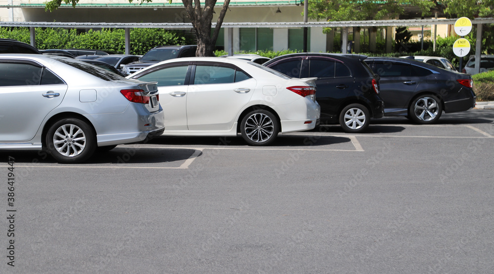 Closeup of rear side of soft blue car with  other cars parking in outdoor parking area in bright sunny day. 