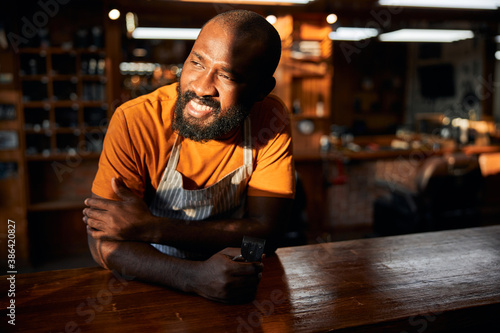 Joyful male barber holding portable hair trimmer