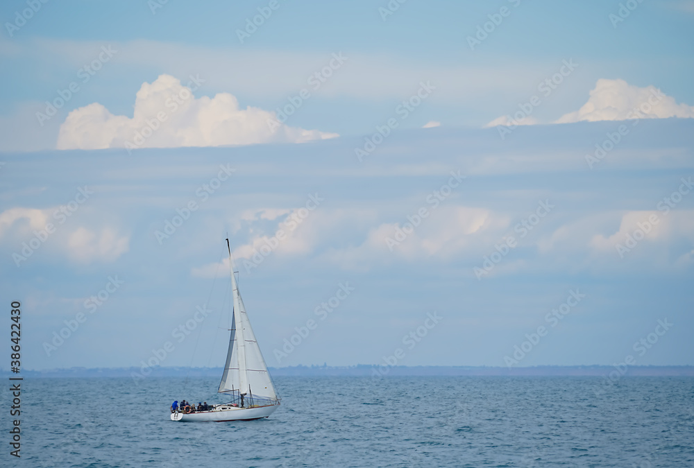 white sailboat in motion against the background of a cloudy sky