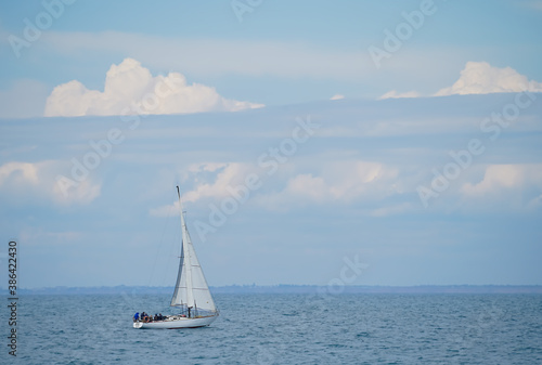 white sailboat in motion against the background of a cloudy sky