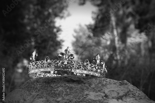 mysterious and magical photo of king crown in the England woods over stone. Medieval period concept. black and white image
