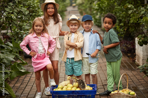 group of diverse children collect lemons and take care of small ducklings in greenhouse, environment and nature concept