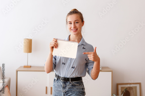 Girl holds a white notepad and shows off