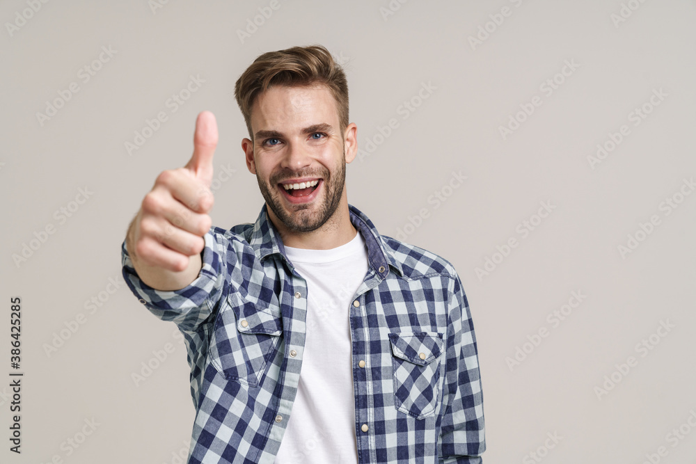 Joyful handsome guy smiling and showing thumb up at camera