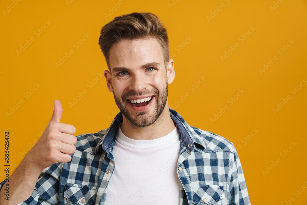 Joyful handsome guy smiling and showing thumbs up at camera Joyful handsome guy smiling and showing thumbs up at camera