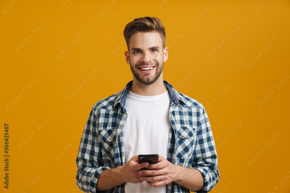Cheerful handsome guy smiling and using mobile phone Cheerful handsome guy smiling and using mobile phone