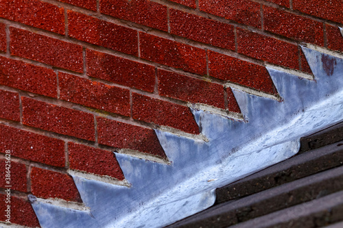 Stepped lead flashing roof gulley creating a water tight seal between roof tiles and brick wall on a domestic house