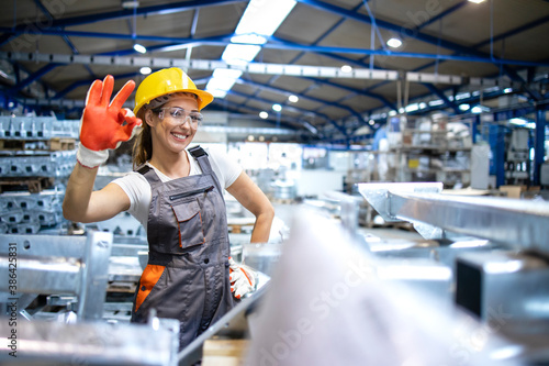 Portrait of female factory worker showing okay sign.