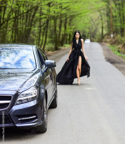 Driver girl. Beauty and fashion. Woman in black dress. Elegant lady escort service worker. Sexy girl elegant dress at road. Escort concept. Glamorous girl and luxury car. Escort and sexual services © be free