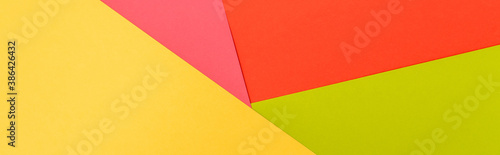 top view of colorful abstract yellow, red, green and pink paper background, panoramic shot
