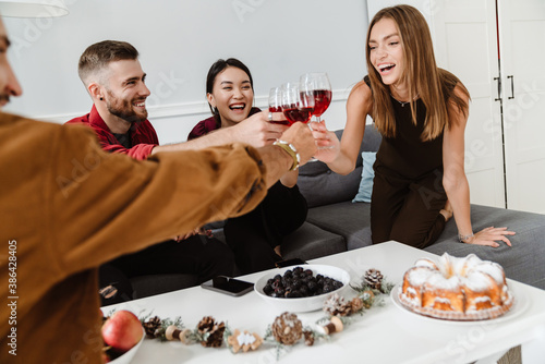 Image of joyful multinational friends eating pie and drinking wine photo