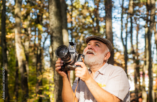 Retro Camera. Capture the moment. Pension and retirement. Vintage stylized photo of man photographer with old Camera. autumn nature background. Smile. Tourist holding the camera. nice weekend in wood