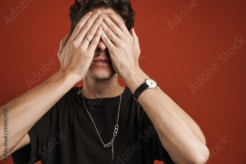 Portrait of a confused man covering his face