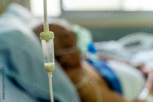 Enteral feeding dropper and a old man patient in the hospital with oxygen mask in the background