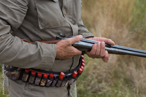 Close up of hunter loading shotgun, holds a gun and ammunition in his hand.