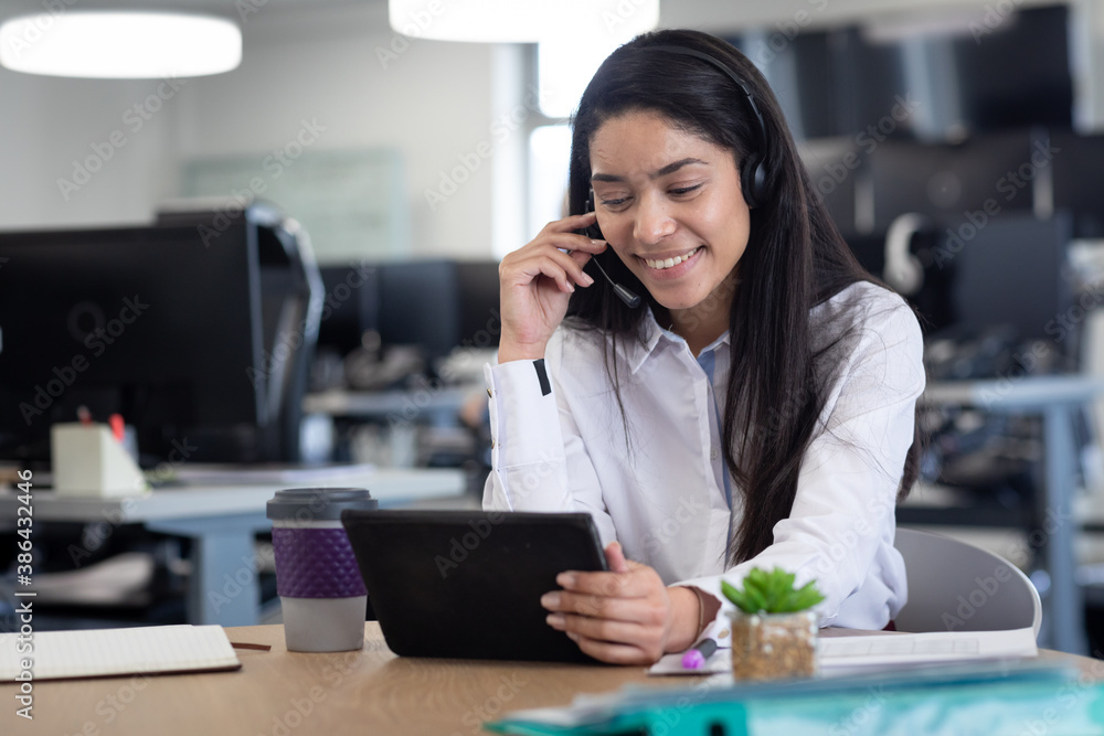 Businesswoman wearing headset using digital tablet at modern office Businesswoman wearing headset using digital tablet at modern office