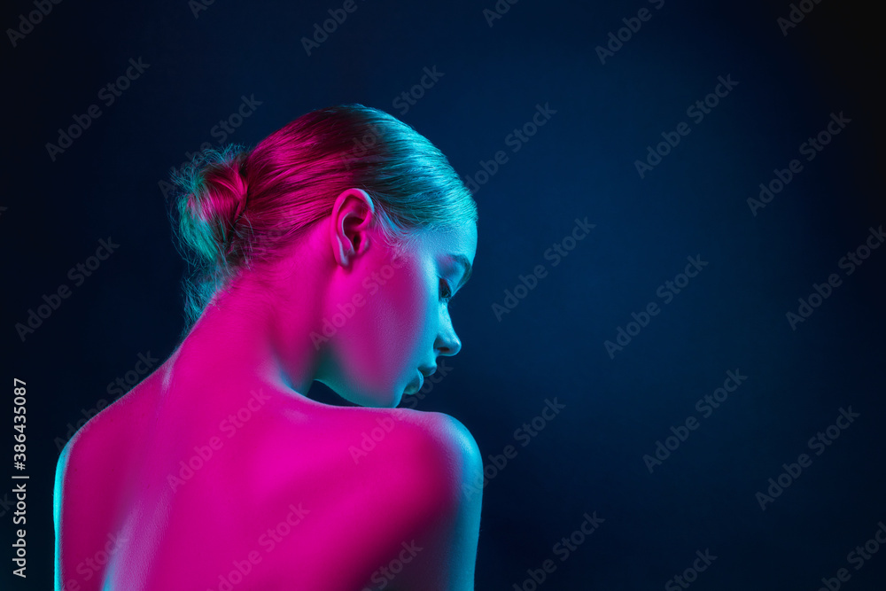 Soft. Portrait of female fashion model in neon light on dark studio background. Beautiful caucasian woman with trendy make-up and well-kept skin. Vivid style, beauty concept. Close up. Copyspace - obrazy, fototapety, plakaty 