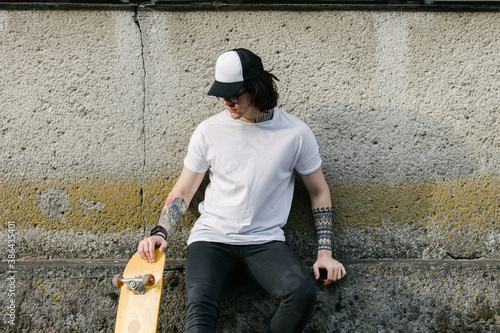 Hipster handsome male model with glasses wearing white blank t-shirt and black jeans with space for your logo or design in casual urban style photo