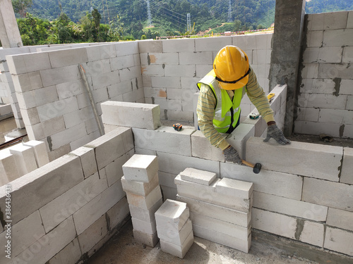 SEREMBAN, MALAYSIA -MARCH 16, 2020: Construction workers laying autoclaved aerated concrete block at the construction site. The use of this material can save time and facilitate construction work.