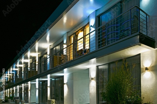 Modern bright residential two-story building with glowing lamps on the facade at night